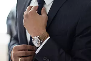 man in nice suit adjusts his tie